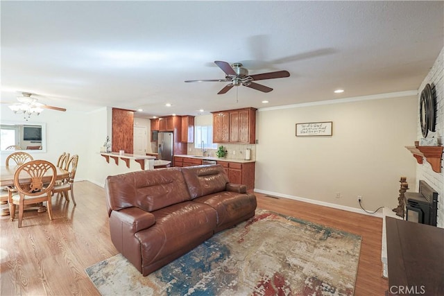 living area with light wood-style flooring, baseboards, a fireplace, recessed lighting, and a ceiling fan