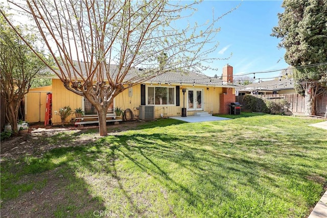 back of property with french doors, a chimney, a deck, fence, and a lawn