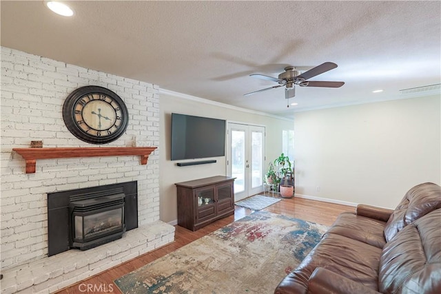 living area featuring a textured ceiling, wood finished floors, a ceiling fan, and ornamental molding