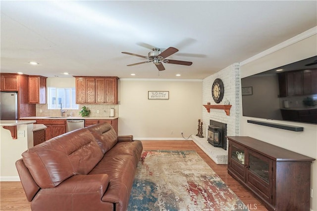 living area featuring ceiling fan, ornamental molding, and light wood finished floors