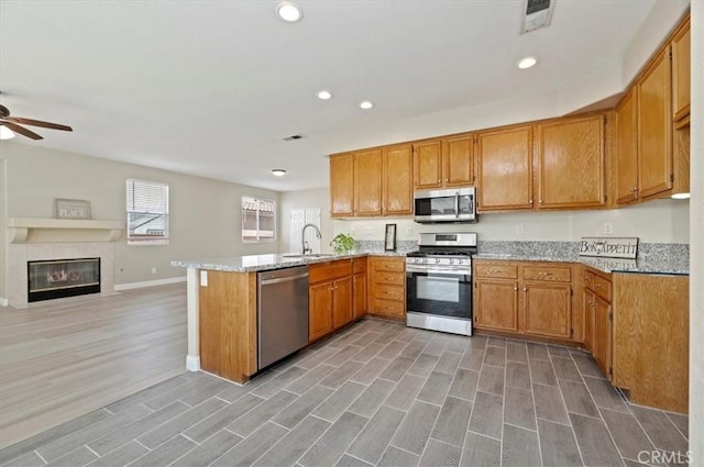 23403 Mountain Song, Murrieta, CA 92562 - kitchen featuring light wood-type flooring, a peninsula, a ceiling fan, appliances with stainless steel finishes, and a sink