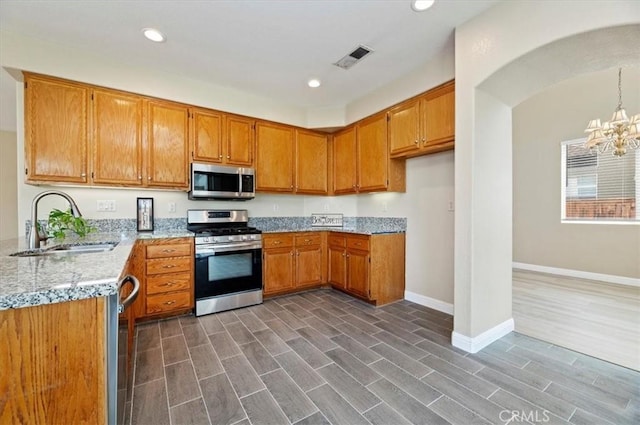 23403 Mountain Song, Murrieta, CA 92562 - kitchen featuring a notable chandelier, baseboards, brown cabinets, appliances with stainless steel finishes, and a sink