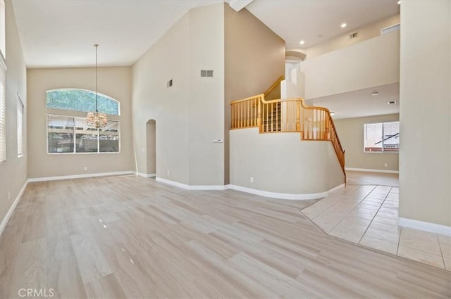 23403 Mountain Song, Murrieta, CA 92562 - unfurnished living room featuring high vaulted ceiling, visible vents, a chandelier, wood finished floors, and stairs