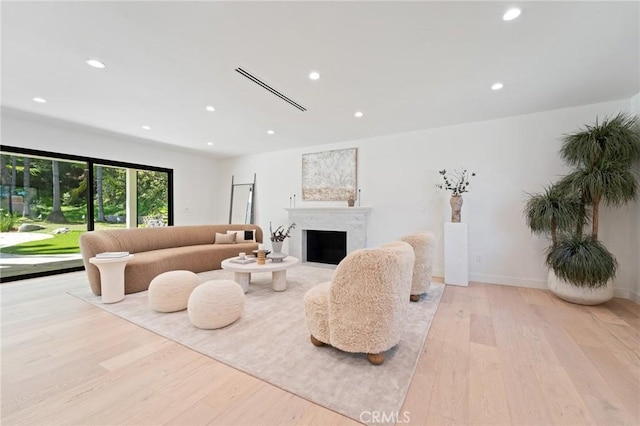 living area with recessed lighting, a fireplace, light wood finished floors, and baseboards