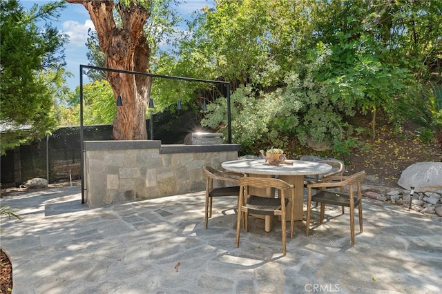 view of patio featuring exterior kitchen, outdoor dining space, and fence