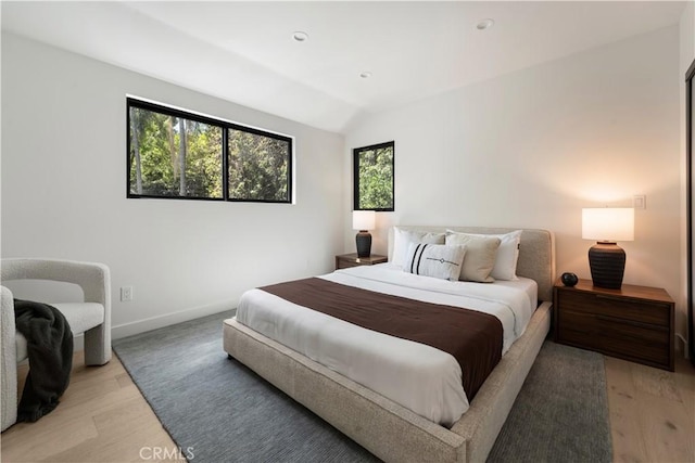 bedroom featuring light wood-style floors, baseboards, and vaulted ceiling