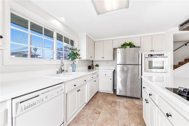 10022 Bismark Dr, Huntington Beach, CA 92646 - kitchen featuring white cabinetry, light countertops, white appliances, stone finish floor, and a sink