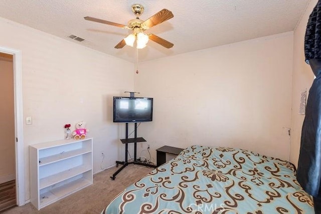 carpeted bedroom featuring a ceiling fan, visible vents, and a textured ceiling