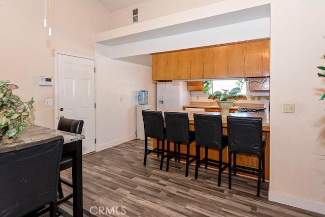 kitchen featuring light countertops, baseboards, visible vents, white fridge with ice dispenser, and wood finished floors