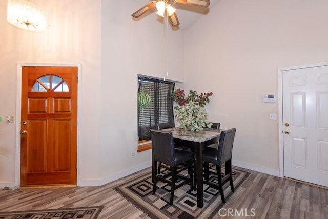 dining space with baseboards, high vaulted ceiling, wood finished floors, and a ceiling fan