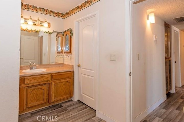 bathroom with baseboards, visible vents, wood finished floors, and vanity