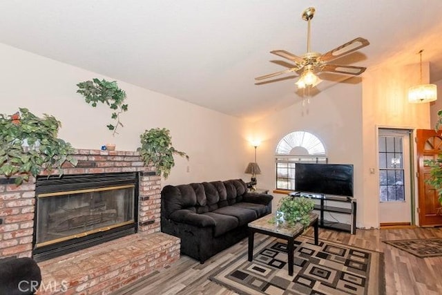 living area featuring a ceiling fan, vaulted ceiling, a fireplace, and wood finished floors