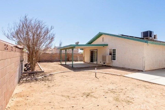 rear view of house featuring stucco siding, central air condition unit, a fenced backyard, and a patio area