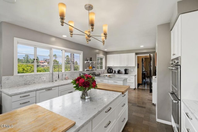kitchen featuring a notable chandelier, recessed lighting, stainless steel double oven, and a sink