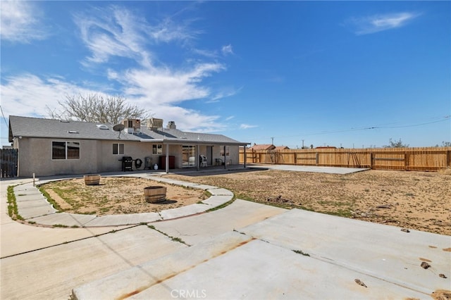 rear view of property with a fenced backyard, stucco siding, and a patio area