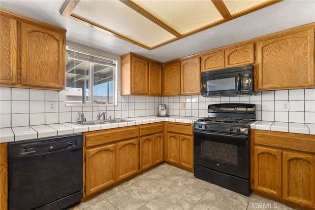 kitchen featuring a sink, black appliances, tile counters, and tasteful backsplash