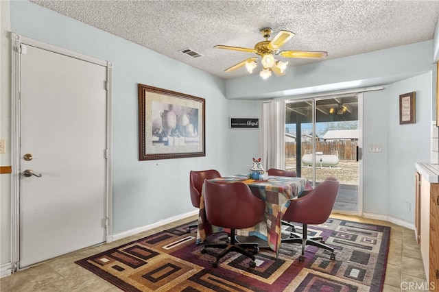 dining space with a textured ceiling, baseboards, ceiling fan, and visible vents