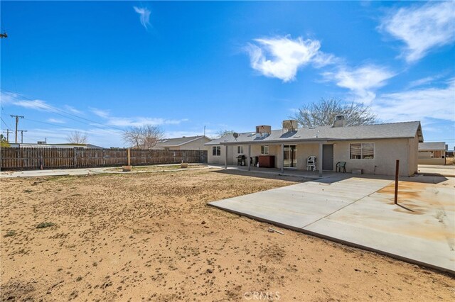 back of property featuring a chimney, stucco siding, fence, and a patio area