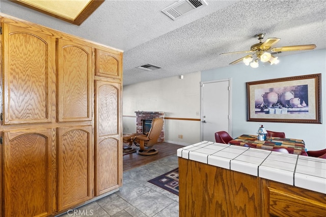 interior space with tile counters, visible vents, a fireplace, and a ceiling fan