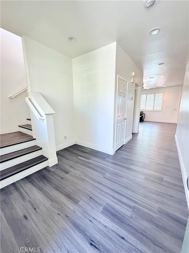 interior space featuring baseboards, stairway, and wood finished floors