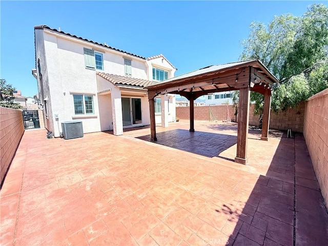 exterior space with stucco siding, a gazebo, a tile roof, and a fenced backyard