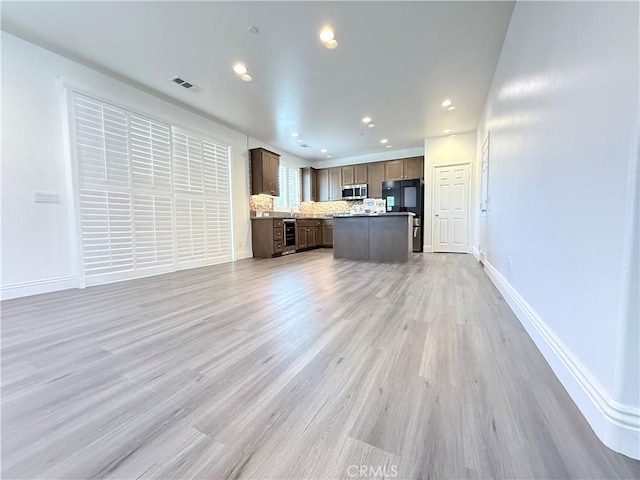 16977 Red Tail Ln, Fontana, CA 92336 - unfurnished living room with beverage cooler, light wood-style floors, baseboards, recessed lighting, and a sink