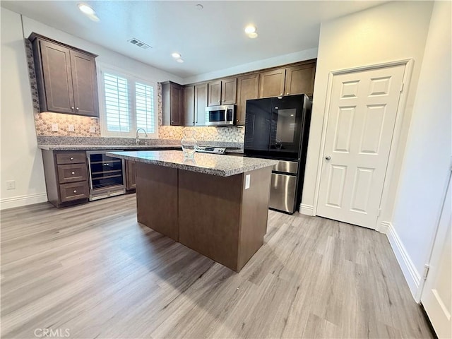 kitchen featuring wine cooler, tasteful backsplash, visible vents, light wood-style flooring, and appliances with stainless steel finishes