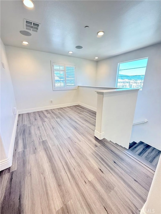 unfurnished room featuring visible vents, baseboards, wood finished floors, and plenty of natural light