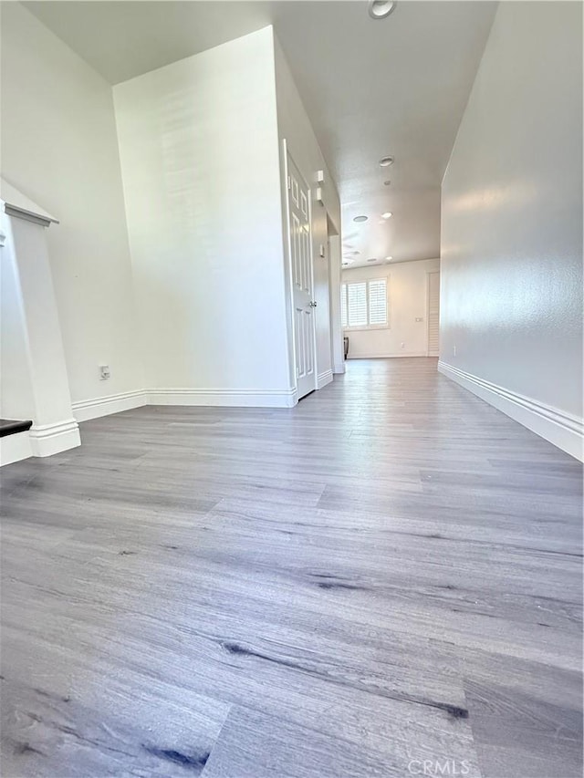 empty room featuring wood finished floors, recessed lighting, and baseboards