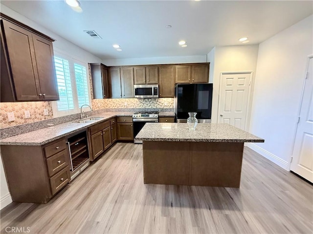 kitchen featuring a sink, visible vents, stainless steel appliances, a kitchen island, and wine cooler