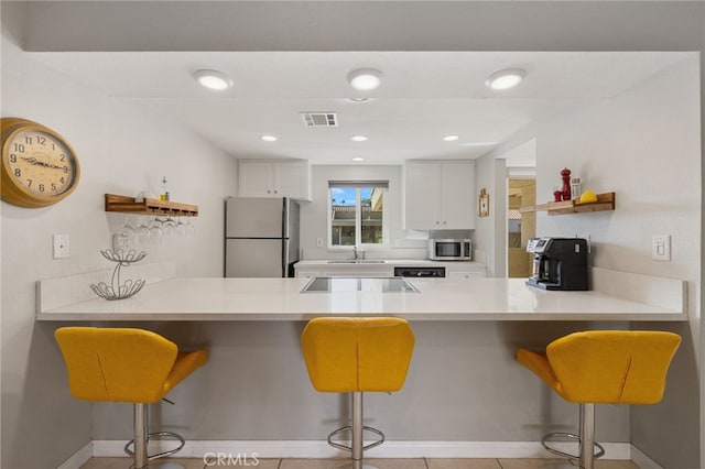 40310 Bay Hill Way, Palm Desert, CA 92211 - kitchen with visible vents, a peninsula, stainless steel microwave, open shelves, and freestanding refrigerator