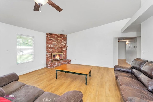 living room with baseboards, ceiling fan, wood finished floors, and a brick fireplace