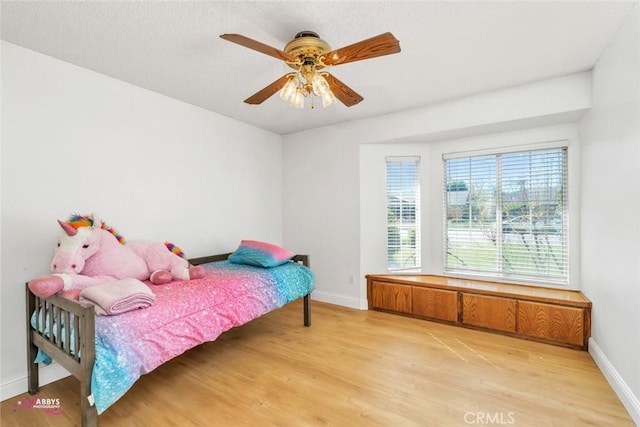 bedroom featuring baseboards, light wood-style floors, and a ceiling fan