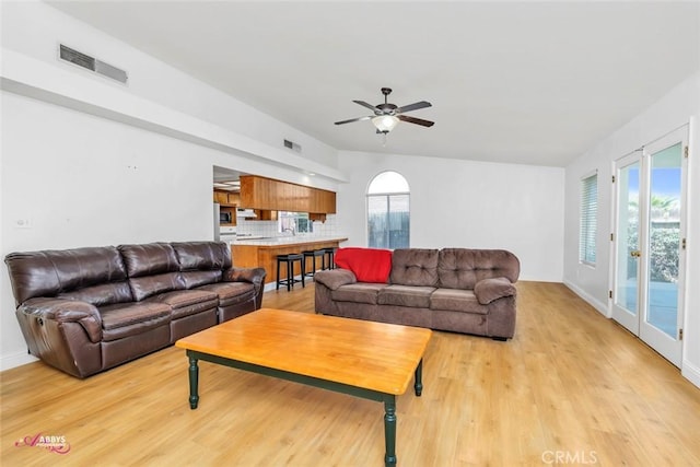 living room with visible vents, light wood-style flooring, and a ceiling fan