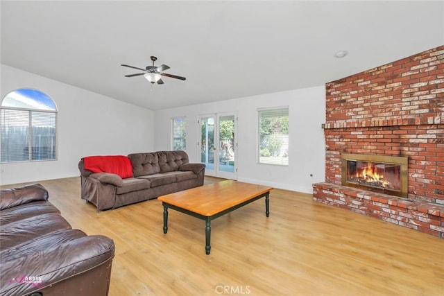 living area with a fireplace, wood finished floors, french doors, and a ceiling fan