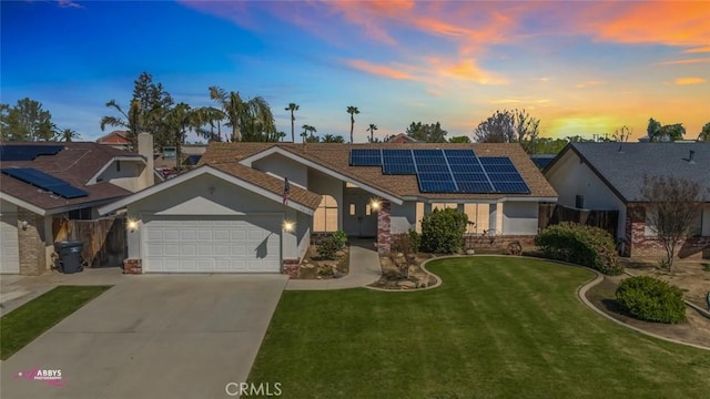 view of front of home with a front yard, concrete driveway, stucco siding, solar panels, and a garage