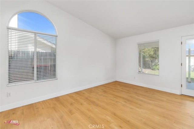 unfurnished room featuring baseboards, light wood-type flooring, and lofted ceiling