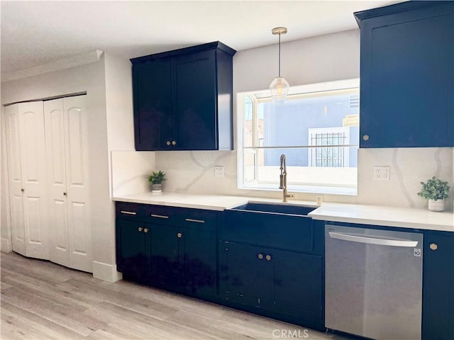 kitchen with light countertops, light wood-style flooring, blue cabinetry, a sink, and stainless steel dishwasher