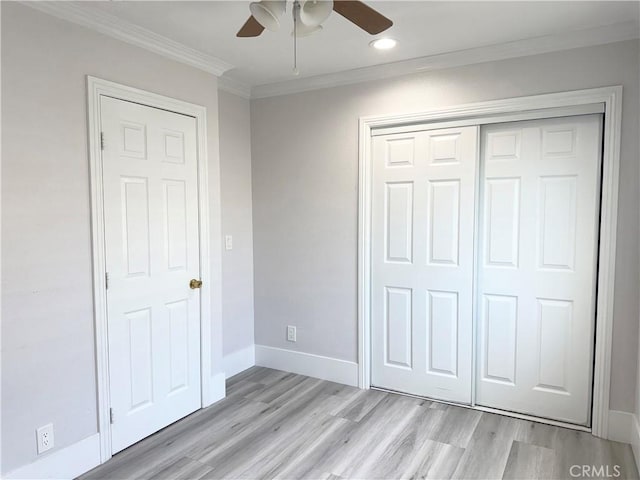 unfurnished bedroom featuring baseboards, a closet, light wood-style floors, and crown molding