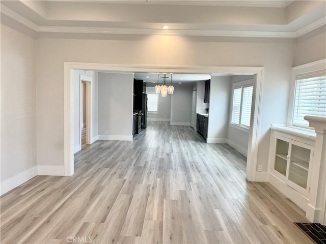 unfurnished living room with baseboards, light wood-style floors, ornamental molding, and a chandelier
