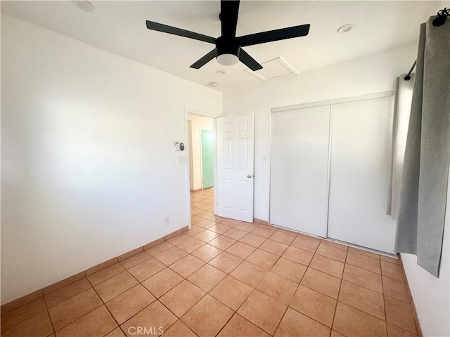 unfurnished bedroom with light tile patterned flooring, a closet, and a ceiling fan