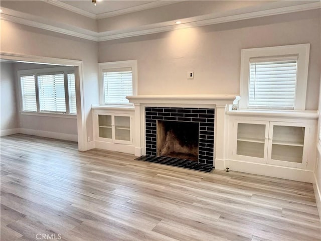 unfurnished living room featuring a fireplace, baseboards, ornamental molding, and wood finished floors