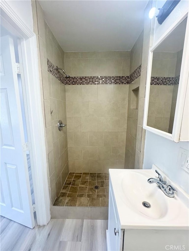 bathroom with tiled shower and vanity