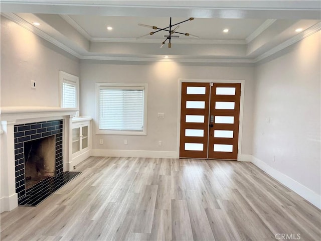 interior space featuring a tray ceiling, baseboards, crown molding, and wood finished floors