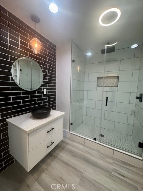 bathroom featuring decorative backsplash, tile walls, a shower stall, wood finished floors, and vanity
