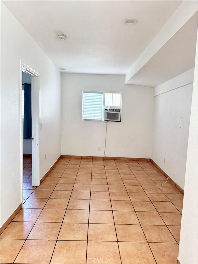 empty room featuring light tile patterned flooring, baseboards, and cooling unit