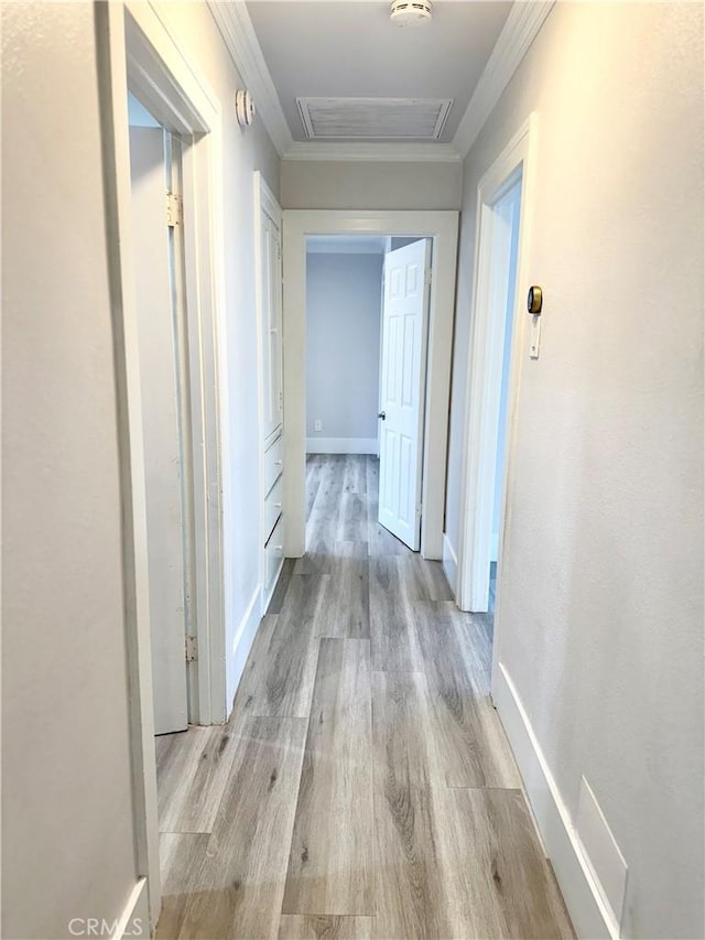 hallway with visible vents, ornamental molding, wood finished floors, and attic access