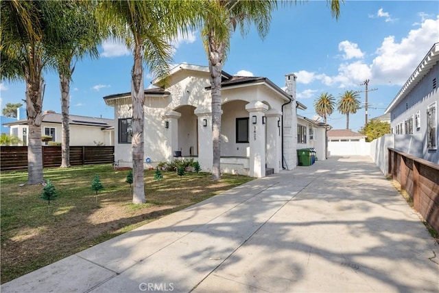view of front of property featuring a front lawn, driveway, stucco siding, and fence