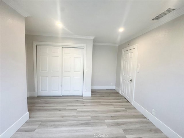 unfurnished bedroom with light wood-type flooring, ornamental molding, baseboards, and visible vents