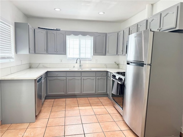 kitchen with light tile patterned flooring, gray cabinets, a sink, appliances with stainless steel finishes, and recessed lighting